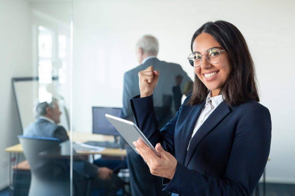 Feliz mujer profesional en gafas y traje con tableta
